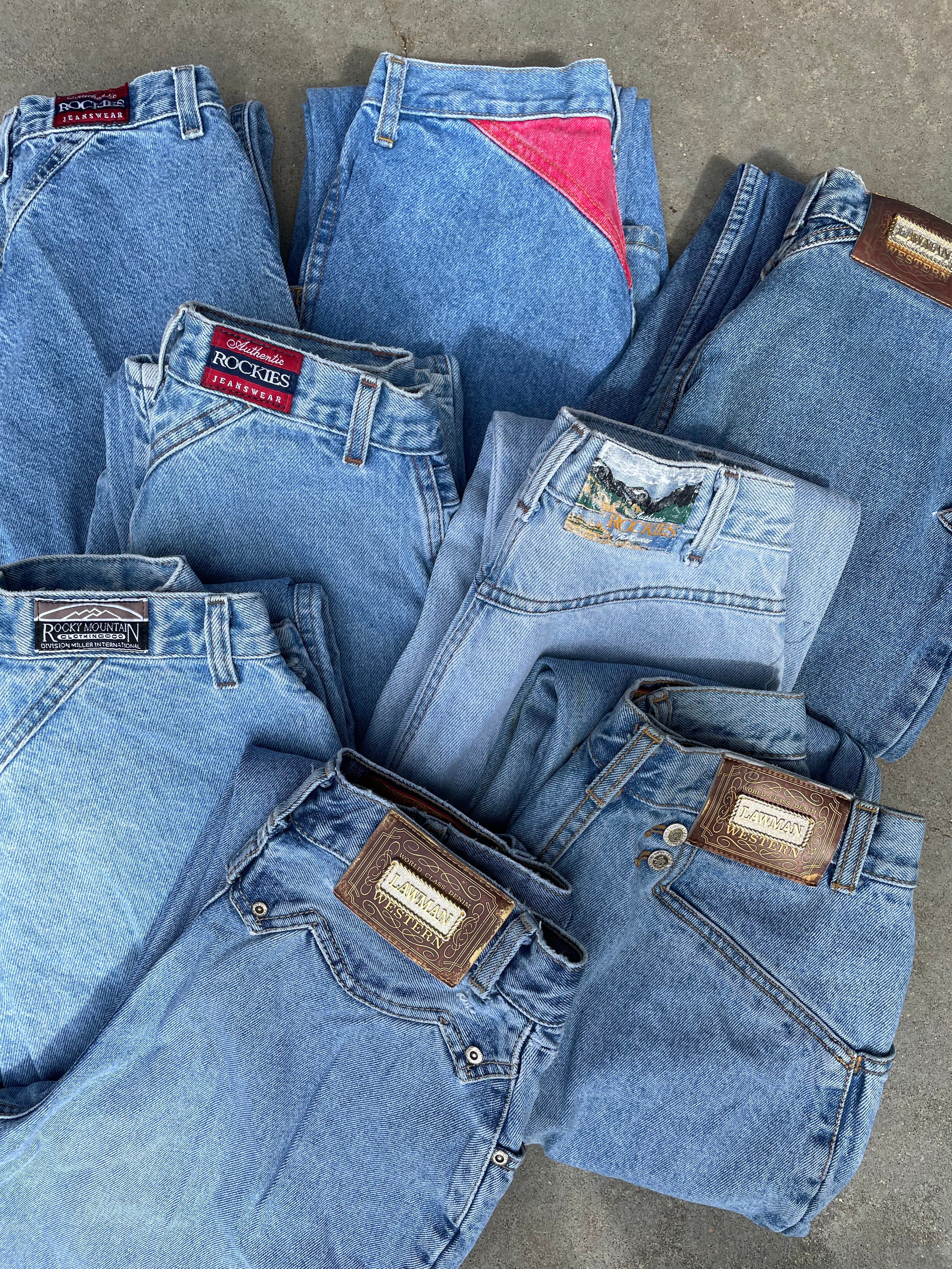 Stack of folded blue jeans with brand labels on a gray surface